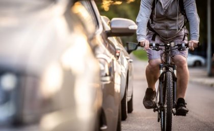 a cyclist riding close to a line of cars